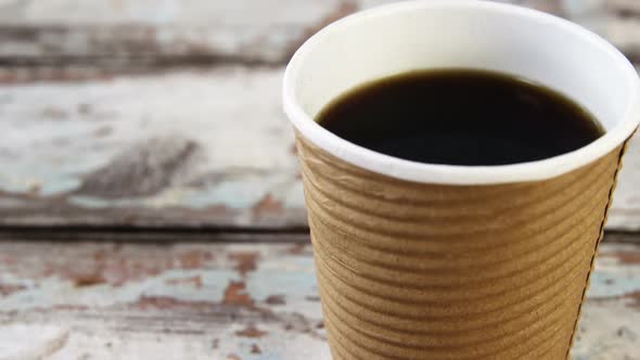 Disposable coffee cup on wooden plank