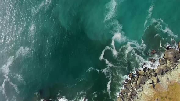 AERIAL: Birds eye view of the rocky shore of the Oregon ocean as the drone moves away from the shore