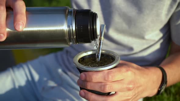 Man Pouring Hot Water Into Yerba Mate Drink From Vacuum Flask. - close up