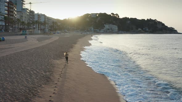 Aerial View of Woman Jogging on Beach at Sunrise