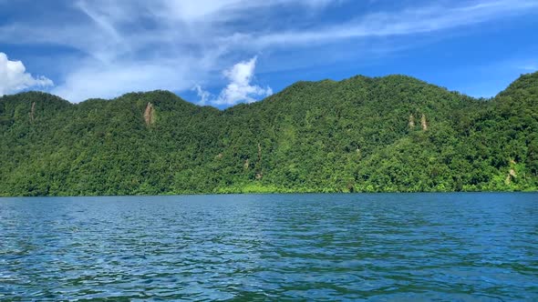 Blue lake against green forest and blue sky in the background.