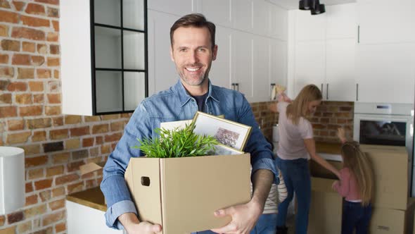 Video portrait of smiling man holding cardboard box during moving.