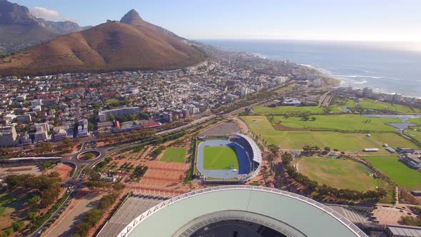 Aerial travel drone view of Cape Town, South Africa with Table Mountain and stadium.