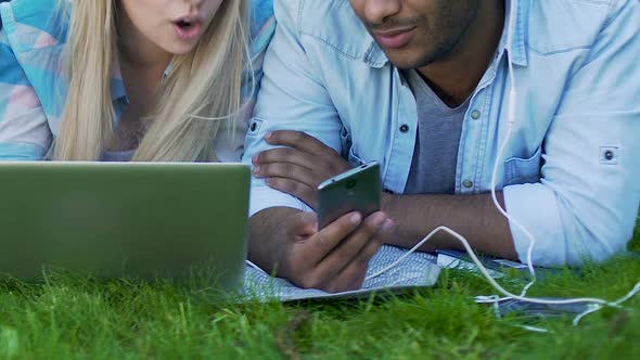 Guy in Headphones With Phone, Girl With Laptop Lying Together on Grass, Friends