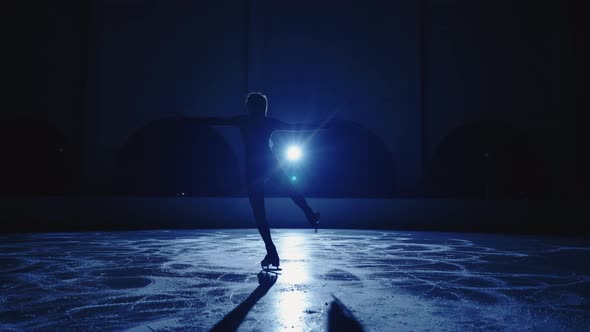 Blurred Silhouette of Figure Skater Girl is Skating on Ice Arena in Darkness Female Figure is Moving