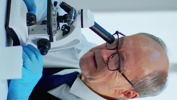 Vertical Video Laboratory Scientist Conducting Experiment Looking at Microscope in Busy Lab