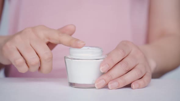 Closeup of Hands Holding Antiaging Treatment Taking Cream with Finger