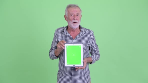 Happy Senior Bearded Man Talking While Showing Digital Tablet