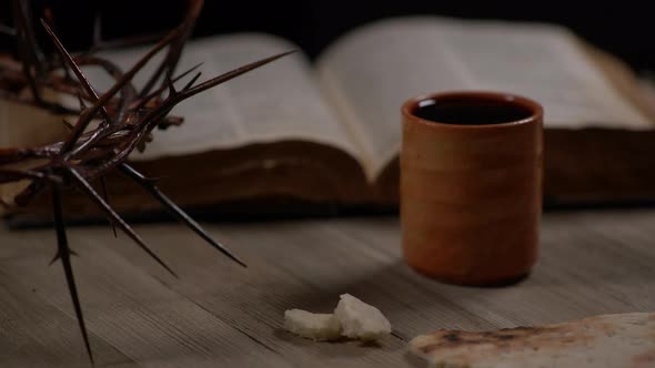 Small Pieces Of Bread Being Placed On Table With Cup, Crown Of Thorns And Bible