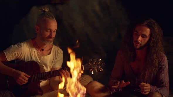 Friends Speaking Smiling Playing on Instruments Sitting Near Bonfire at Night Beach