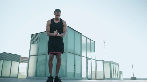 Bald strong sportsman wearing black T-shirt does lunges with an elastic band to the sides