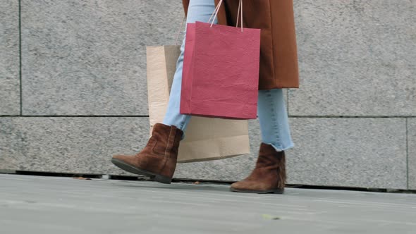 Closeup Female Legs in Jeans Brown Shoes and Coat Walking Along Sidewalk in City on Street