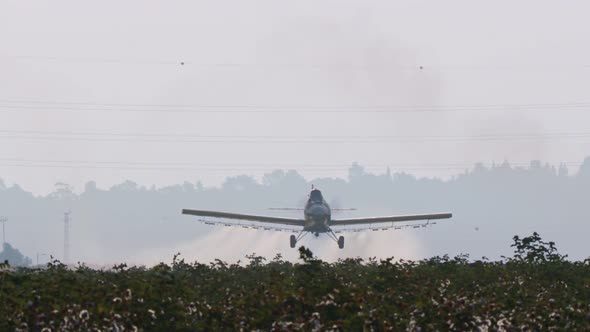 Crop duster spraying chemicals over a cotton field - slow motion