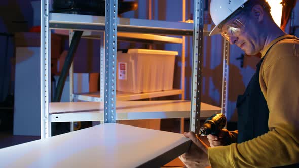 Worker Wearing Hard Hat Assembles the Industrial Shelf Rack