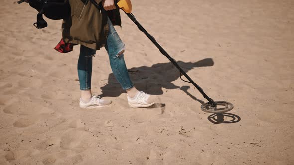 Unrecognizable Person Scanning the Sand with Metal Detector To Find Lost Precious Metals.