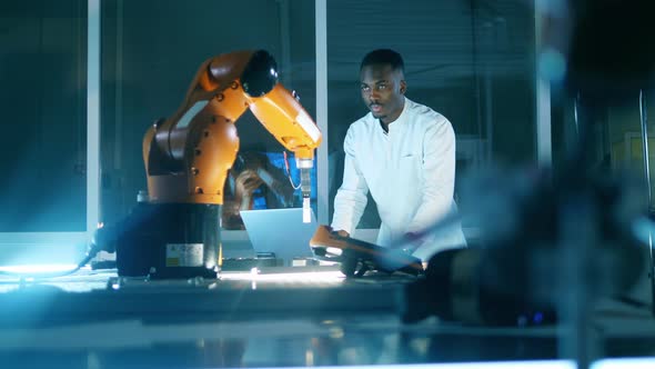 African Man Is Using a Laptop To Manage a Robotic Device