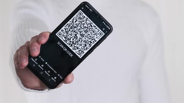 Male Hand Shows QR Code on Smartphone on White Background