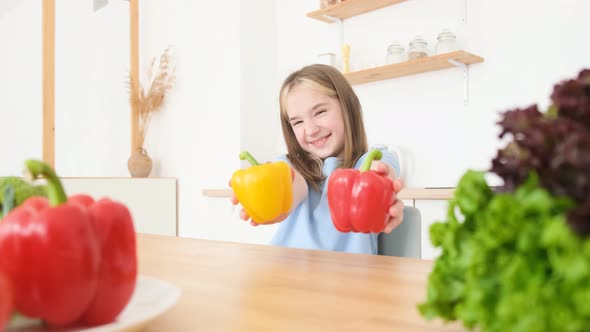 The Little Girl is a Vegetarian She is Smiling and Holding Yellow and Red Peppers