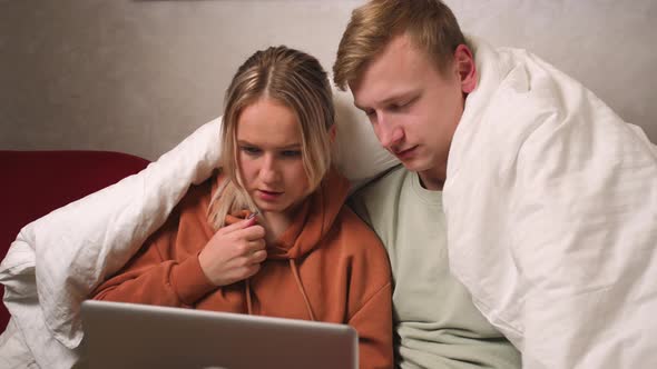 The Couple Man and Woman Watching a Movie on a Laptop on Sofa at Home