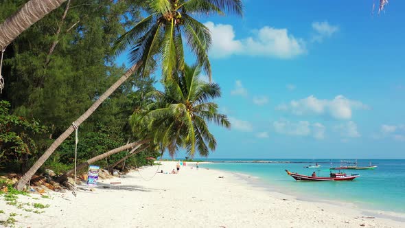 Boats floating near the sandy beach with palms. bright blue sky on a sunny day on tropical island.