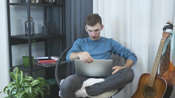 Young man starting to work on laptop computer from home office.