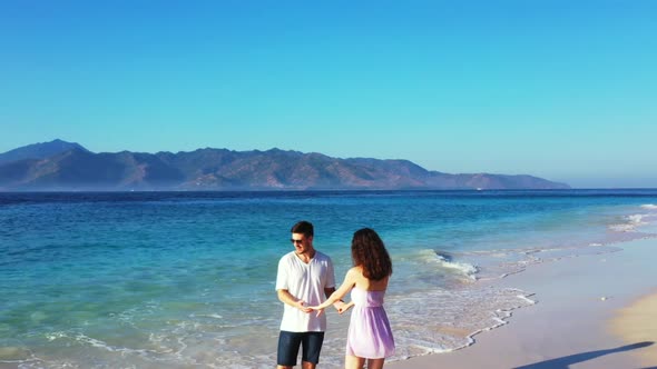 Family of two relax on tropical shore beach wildlife by blue sea with white sandy background of Gili