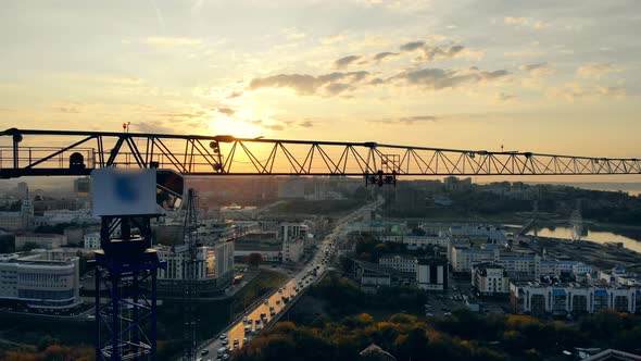 Building Crane and the Sunset Cityscape. Modern Construction Site at Sunset, Aerial View