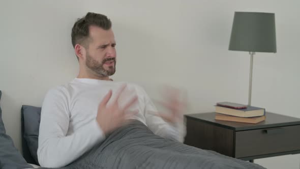 Man Feeling Worried While Sitting in Bed