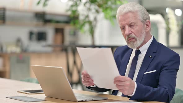 Senior Old Businessman with Laptop Reading Documents