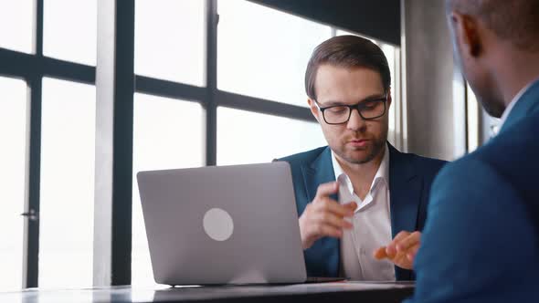 Two colleagues in suits talking at the desk