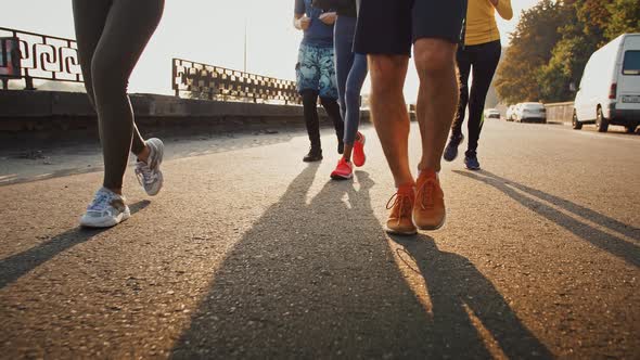 Close Up of Sporty People Legs Running on Sidewalk Early in Morning Slow Motion