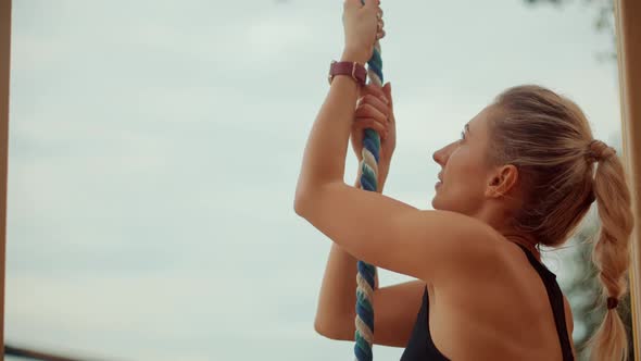 Woman Exercising On Climbing Rope. Workout Outdoor On Public Gym. Fit Athlete Girl Climbing Up.
