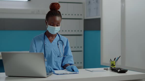 Portrait of Nurse Sitting at Desk with Laptop and Documents