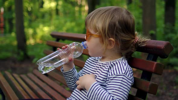 Cheerful Little Girl in Striped Tshirt and Orange Glasses Open Bottle and Drinks Clean Ecological