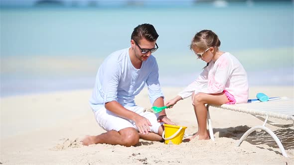 Father and Little Girl Making Sand Castle at Tropical Beach