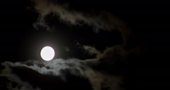 A Full Moon Moves Across the Dark Sky