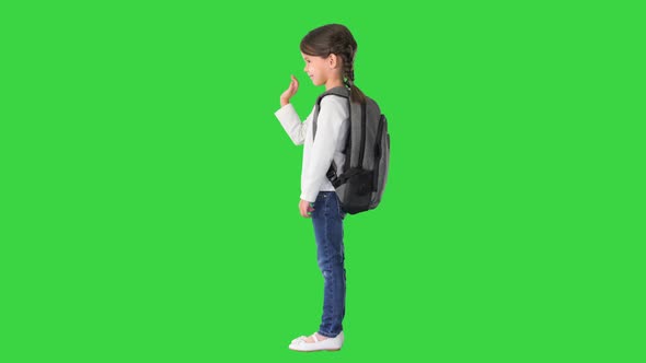 Cute Little Schoolgirl with Backpack Waving Her Hand on a Green Screen Chroma Key