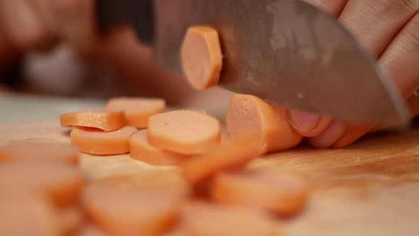 Close up of a knife cuts the sausage into small pieces.