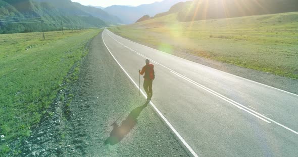 Flight Over Hitchhiker Tourist Walking on Asphalt Road. Huge Rural Valley at Summer Day. Backpack alt