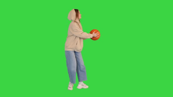 Casual Girl Dancing Holding Basketball on a Green Screen Chroma Key