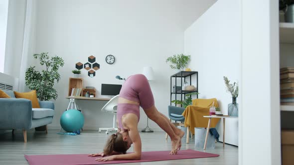 Portrait of Skilled Young Lady Standing Upside Down Enjoying Yoga Practice at Home