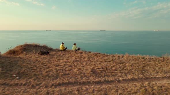 Two Travelers with Dog Sitting on the Edge of Cliff and Overlooking the Black Sea