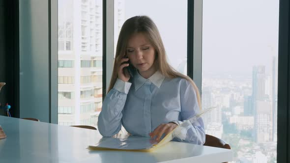 Concentrated Businesswoman Sitting in Office and Using Smartphone