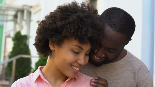 Afro-American Couple Enjoying Date, Girl Feeling Safe in Boyfriend Arms, Smiling