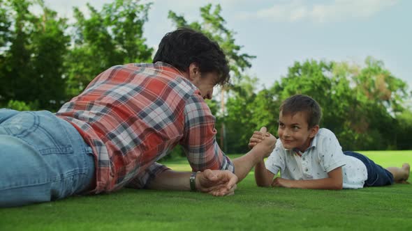 Father and Son Practising Arm Wrestling in Meadow. Boy Winning Competition