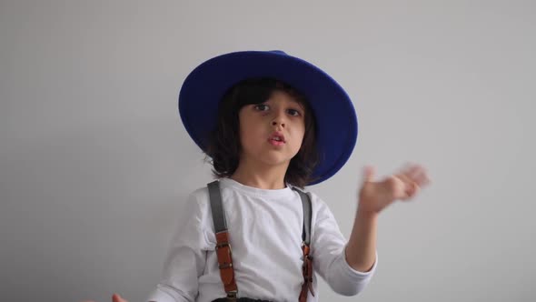 Boy Dances at Home in a Blue Hat with a Brim and a White Tshirt
