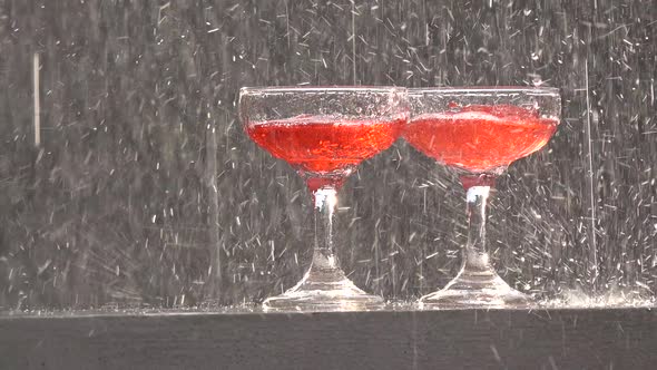 Two glasses of red wine on a wall in a thunderstorm.