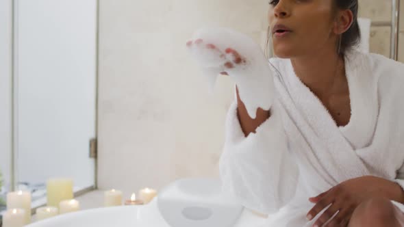 Mixed race woman sitting by a bathtub at home