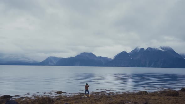 Man taking photo on shoreline of cold tranquil lake