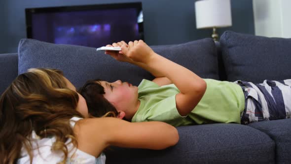 Siblings using digital tablet in living room